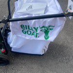 White bag with a green Billy Goat logo mounted on a bicycle trailer, filled with papers wrapped in tissue.