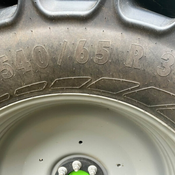 Close-up of a dirty tire sidewall showing embossed size markings and a portion of the wheel with a green valve stem cap in the center.