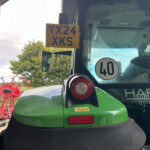 Yellow plate with 'YX24 XKS' mounted inside the cab of a green tractor, visible near the windshield.