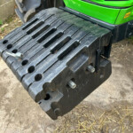 Green excavator with black rubber tracks resting on dirt.