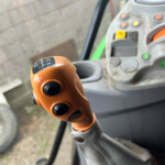 Close-up of an orange gear shift knob in the cab of a vehicle, with a control panel and buttons in the background