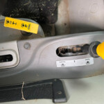 Close-up of a car's driver-side floor and center area: a yellow lever labeled Eco/Normal with gray surrounding panels and a yellow round knob nearby.