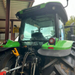 Front view of a green Deutz-Fahr tractor inside a shed, showing the cab and front lights.