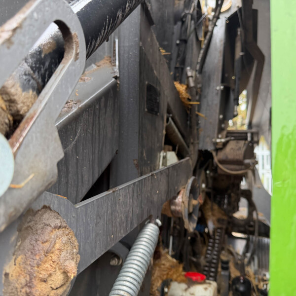 Close-up of rusted industrial machinery with metal frames and hoses, against a green panel.