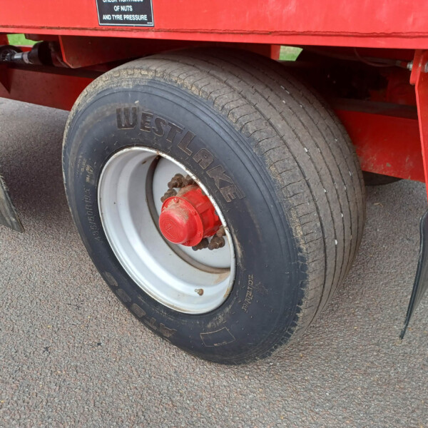 Close-up of a large truck trailer wheel mounted on a red trailer, showing a Westlake tire, metal rim, and red hub cap.