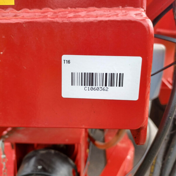 Close-up of a red metal machine with a white barcode label reading 'T16' and 'C1060362' on it.