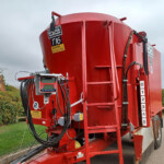 Red industrial tanker trailer with multiple hoses and a side-mounted control panel and safety stickers visible.