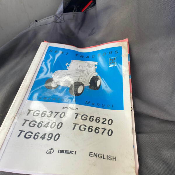 Open ISEKI tractor operator's manual with a blue cover showing a illustrated tractor, model numbers like TG6370 TG620, on a gray seat.