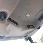 Interior of a vehicle cabin ceiling with a small overhead light, vents, and a control panel nearby