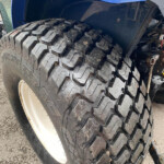 Close-up of a mud-terrain tire on a heavy-duty truck with a blue fender above.