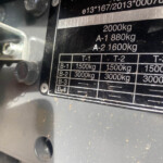 Close-up of a metal load-rating plate on industrial equipment showing capacities like 2000 kg and A-1 880 kg, A-2 1600 kg, with bolts nearby