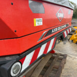 Red KUHN agricultural machine with 'AXIS 20.2 MEMC' branding and a FAROL sticker, outdoors on wooden pallets.