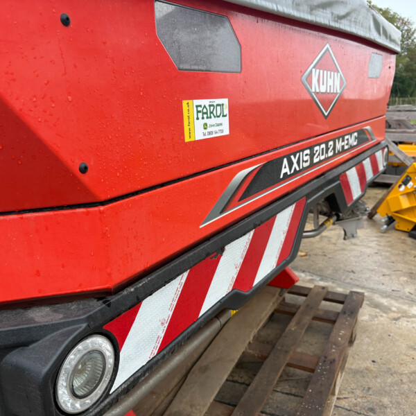 Red KUHN agricultural machine with 'AXIS 20.2 MEMC' branding and a FAROL sticker, outdoors on wooden pallets.