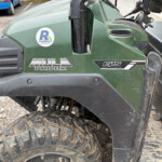 Close-up of a green Mule Pro-FX utility vehicle with muddy tires and a Russell sticker.