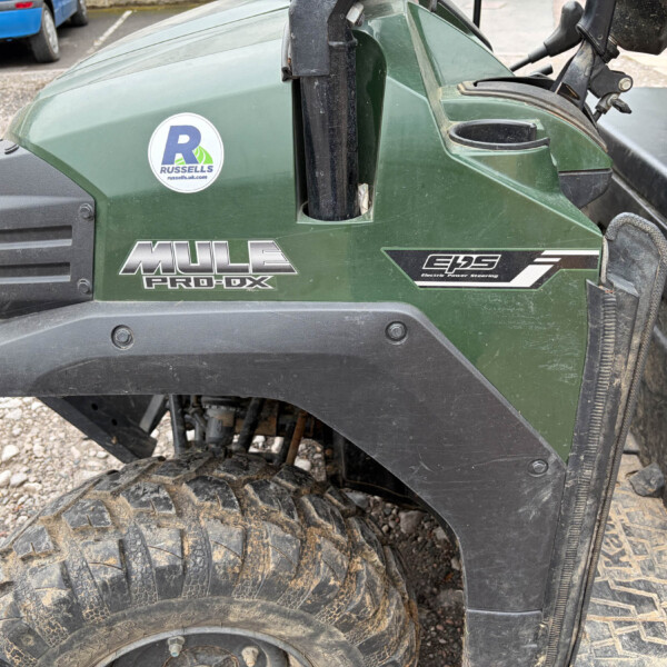 Close-up of a green Mule Pro-FX utility vehicle with muddy tires and a Russell sticker.