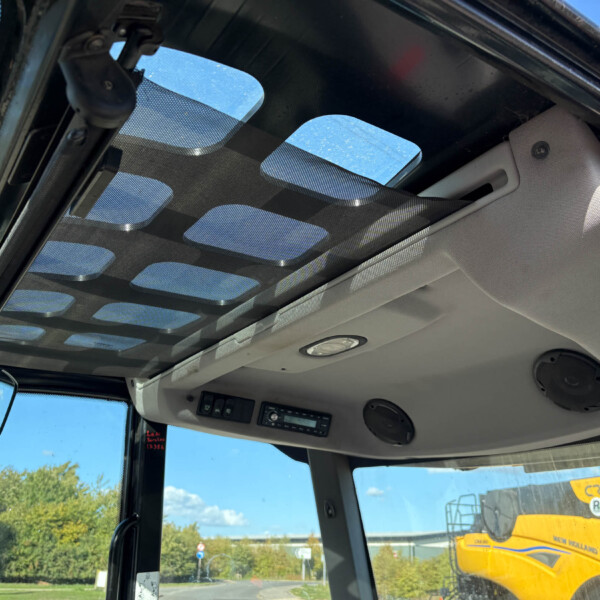 Interior of a truck cab showing overhead skylight panels and sunroof openings with blue sky outside