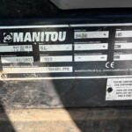Close-up of a dirt-covered equipment data plate showing MANITOU branding and weight/serial information.