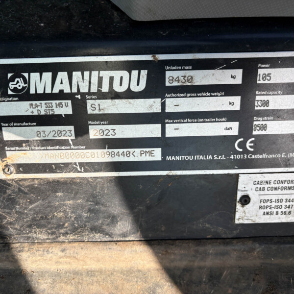 Close-up of a dirt-covered equipment data plate showing MANITOU branding and weight/serial information.