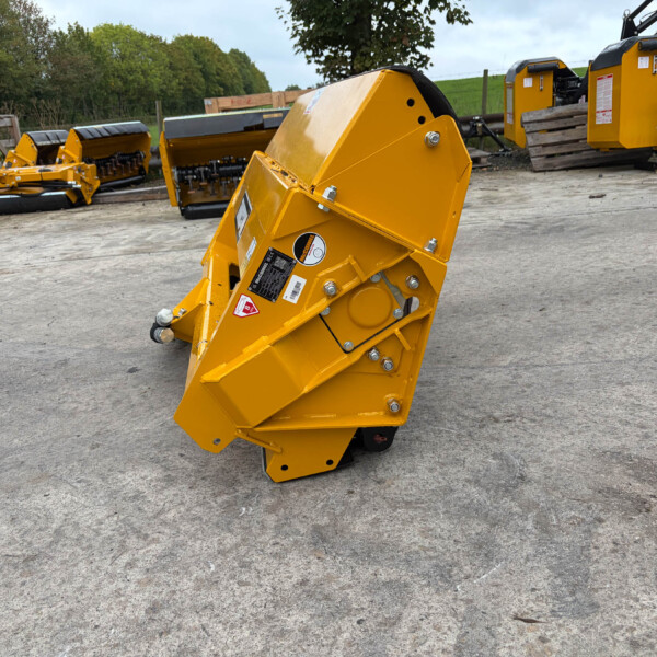 Yellow industrial machinery with large angled housing in a yard, multiple machines in background and trees beyond.