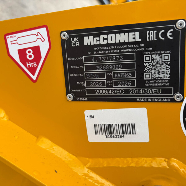 Close-up of a yellow machine showing a red 8 Hrs service sticker and a black metal identification plate with model and serial numbers.