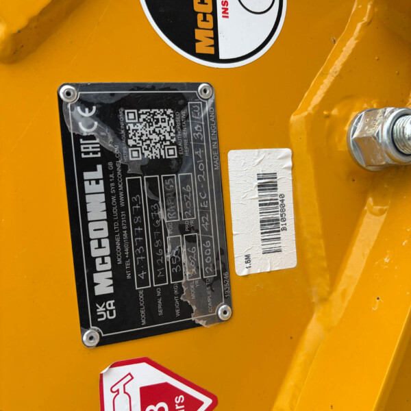 Close-up of a yellow industrial machine showing a black data plate with a QR code, serial numbers, and a red '8 hrs' warning sticker nearby.