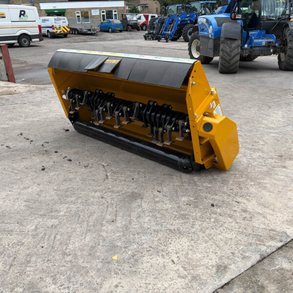 Yellow industrial snow plow attachment on a concrete yard with blue tractors and service vans in the background