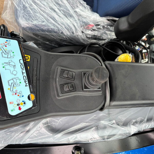 Close-up of a car's center console with a diagram sticker, red emergency button, and exposed wiring under plastic wrap.