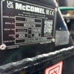 Close-up of a black metal equipment label showing model code 7250986 and serial number M2583758 with a QR code nearby.