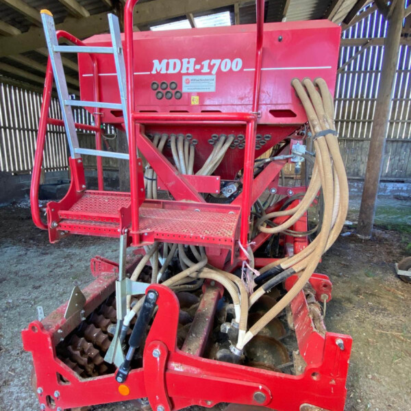 Red MDH-1700 farming machine with hoses protruding, inside a barn or shed.