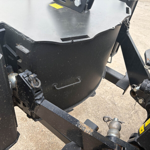Close-up of a black industrial machine frame with hitch and hydraulic components, showing dirt and wear.