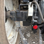 Close-up of a dirty trailer undercarriage showing suspension components, Bolts, and hoses near a wheel rim.