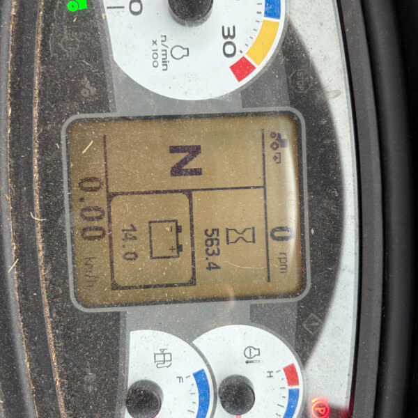 Dashboard of a dusty tractor showing a circular speed gauge with colored zones and a green tractor icon, gear in neutral (N) on the digital display, several warning/indicator lights.