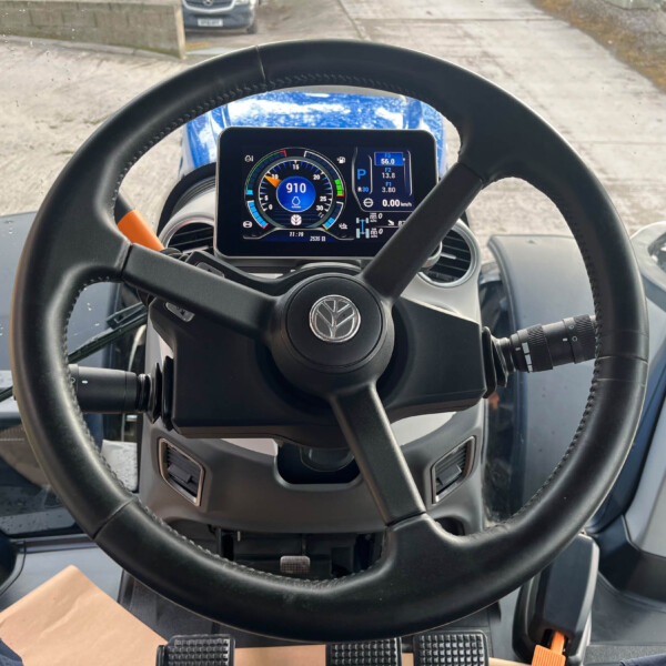 Interior view of a vehicle cabin with a large steering wheel and digital instrument cluster displaying RPM and gear information.