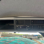View of an overhead vehicle dashboard console with hazard switch and multiple buttons, seen from the windshield down view inside the cabin