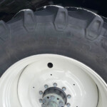 Close-up of a large off-road tire mounted on a white wheel with chunky tread lugs visible in the image surface. (informative)