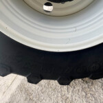 Close-up of a white wheel rim next to a rugged black tire with dirt specks and tread blocks visible.
