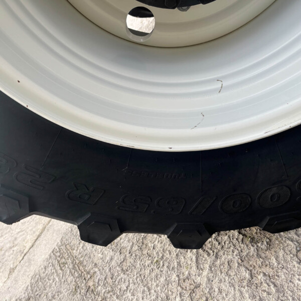 Close-up of a white wheel rim next to a rugged black tire with dirt specks and tread blocks visible.