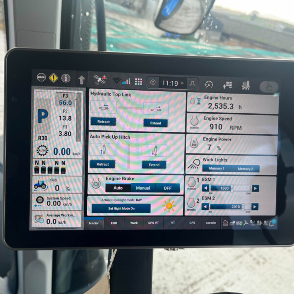 Tablet mounted in a tractor cab displaying a multi-panel system monitor with engine hours, speed, hydraulics, and other controls