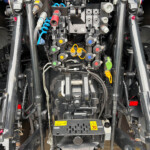 Close-up of a tractor's rear hydraulic manifold with colored levers, hoses and fittings.