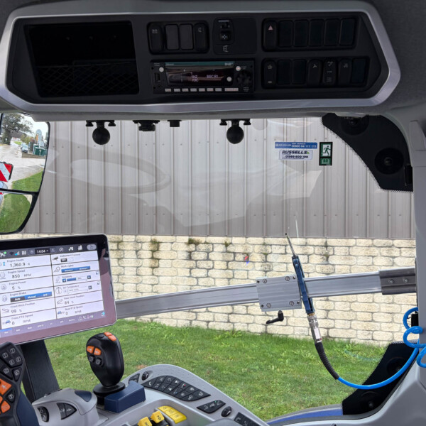Interior of a truck cab with a mounted touchscreen display showing vehicle data and controls above the dashboard path to a driver joystick and windshield view behind.