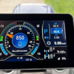 Close-up of a car’s digital instrument cluster showing a circular tachometer with blue accents and a parked gear indicator (P).