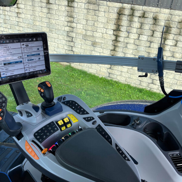 Inside a tractor cab with a touchscreen display showing engine data, joystick, and control panels