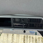 Dashboard center console with a row of black switches, hazard button, and touchscreen radio system.