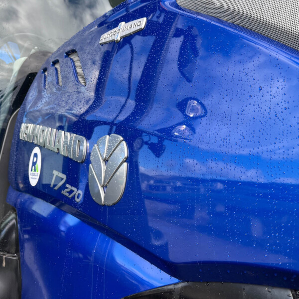 Close-up of a blue truck door with a chrome AUTOCOMMAND badge and raindrops on the glossy surface.