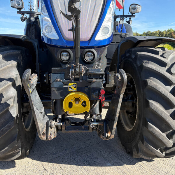 Front view of a blue tractor with oversized front tires and heavy hitch, facing the camera.