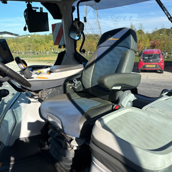 Inside a modern truck cab with a blue-trimmed driver’s seat, a tablet mounted on the left, and a parking lot visible through the windshield.