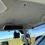 Gray truck-cab ceiling with built-in speakers and overhead console, windshield showing blue sky outside