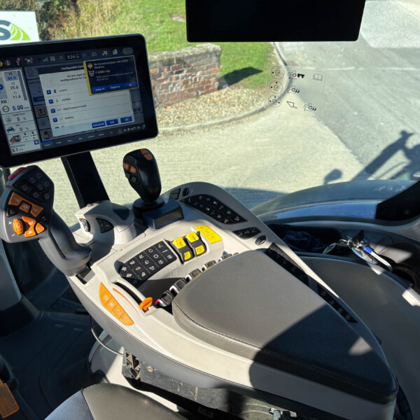 Inside a tractor cab with a mounted tablet showing control settings and gauges on a screen.