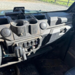 Close-up of a rugged vehicle dashboard showing cup holders, vents, and multiple switches along the center console.