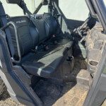 Polaris side-by-side interior with two black seats, steering wheel, and dirt-streaked floor.